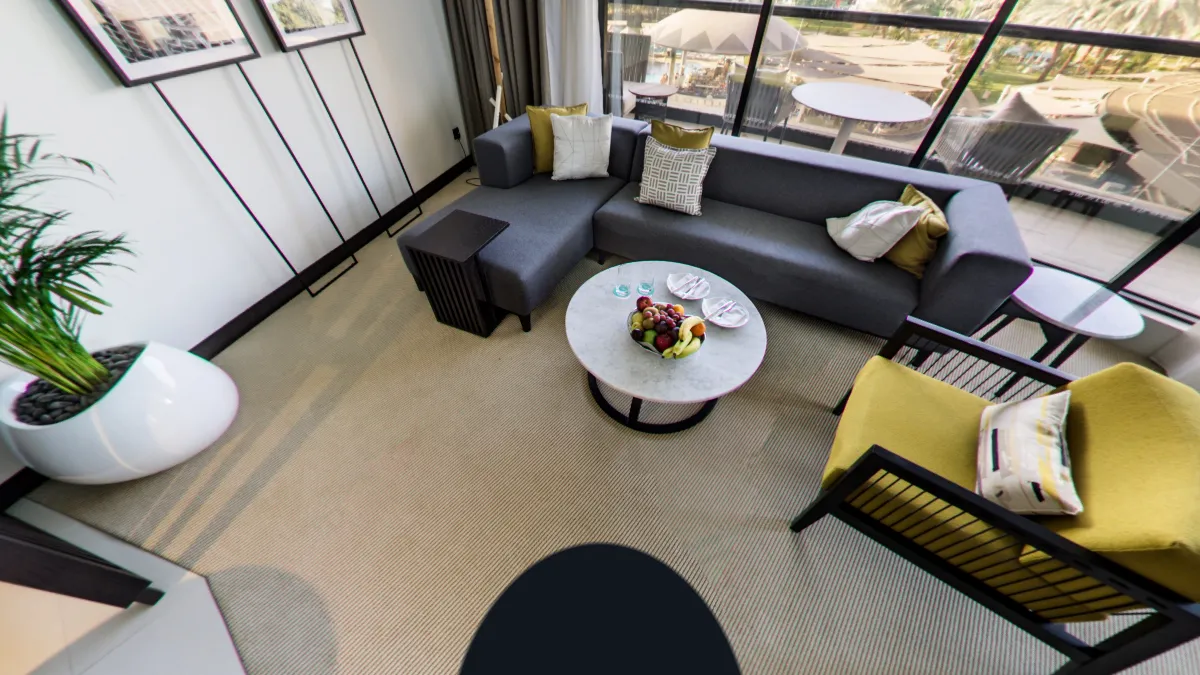 A hotel lounge in a 360° tour seen looking down, with a dark round patch on the carpet where the tripod stood